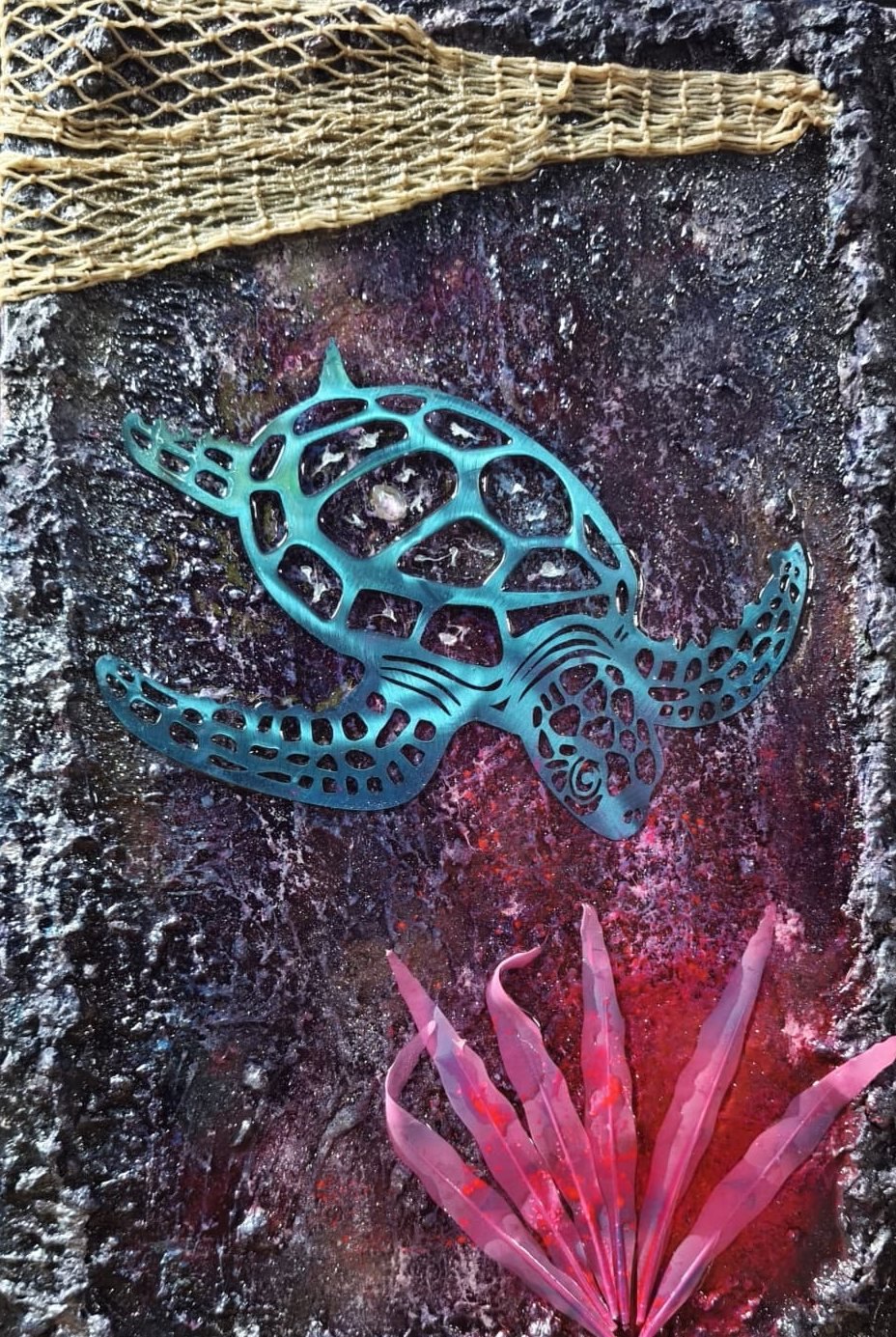 Rau verkrustetes Relief in Violett und Rot mit türkiser Schildkrötenfigur, rosa Pflanze und Netz am oberen Rand
